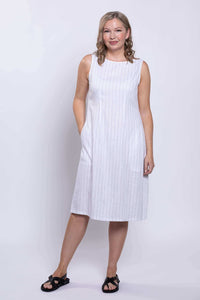 Front view of woman standing in white sleeveless striped dress with relaxed pose