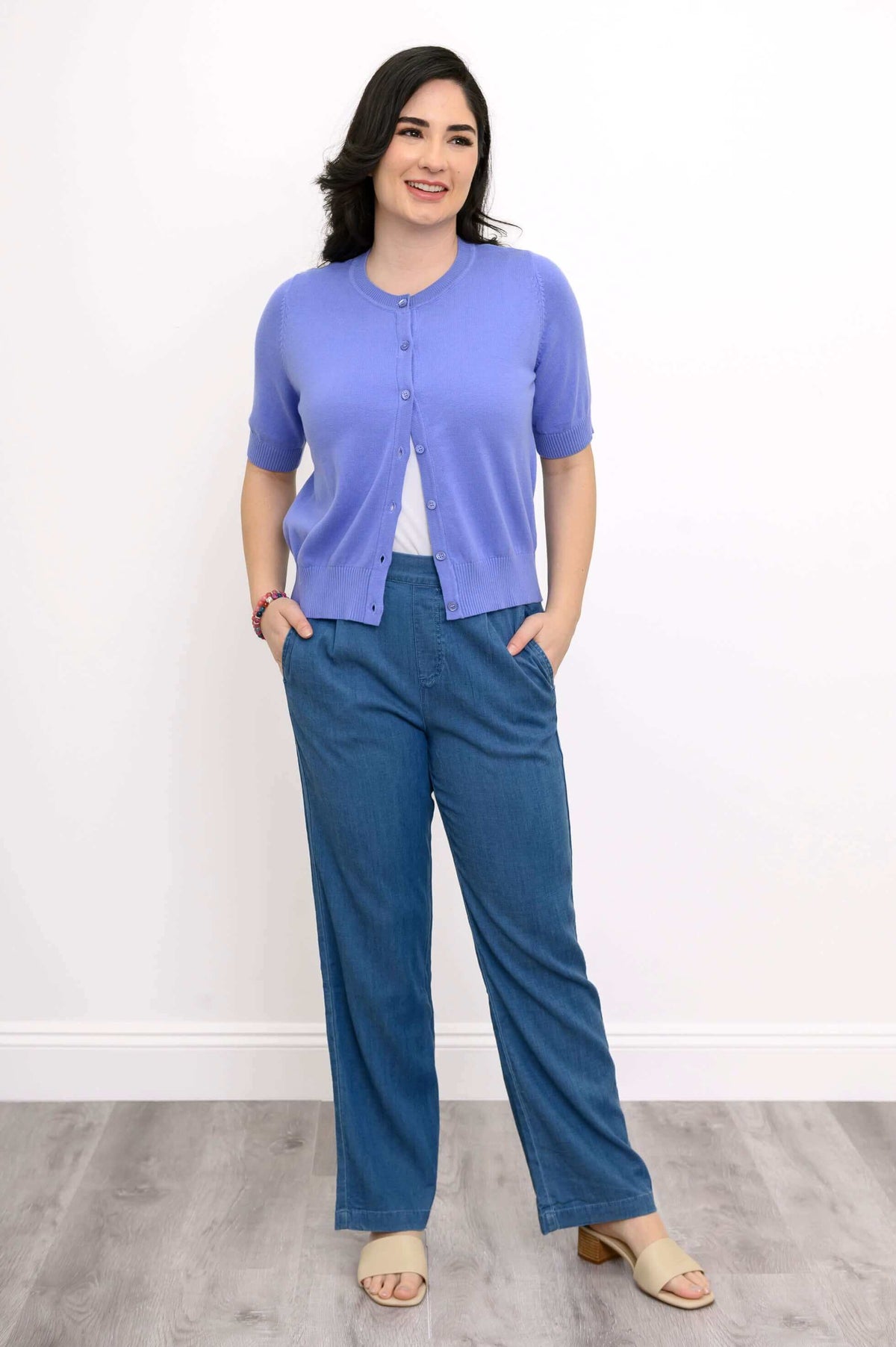 Woman posing in a retro-style short sleeve purple cardigan with blue wide-leg pants
