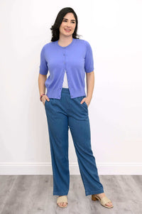 Woman posing in a retro-style short sleeve purple cardigan with blue wide-leg pants