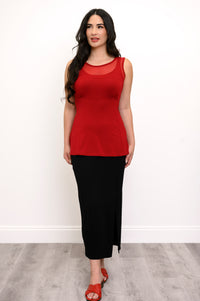 Full body view of woman wearing a red tank top with mesh detail, black skirt, and red sandals
