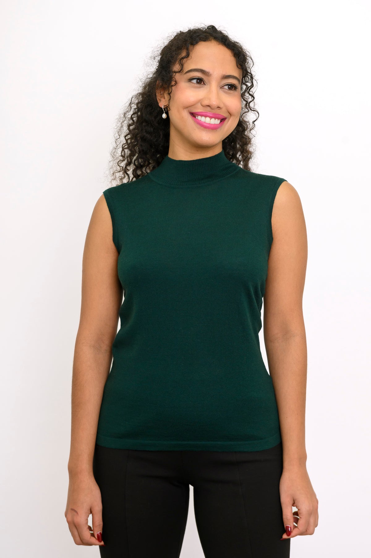 Front view of a woman wearing a comfortable dark forest green sleeveless knit top on a white backdrop.