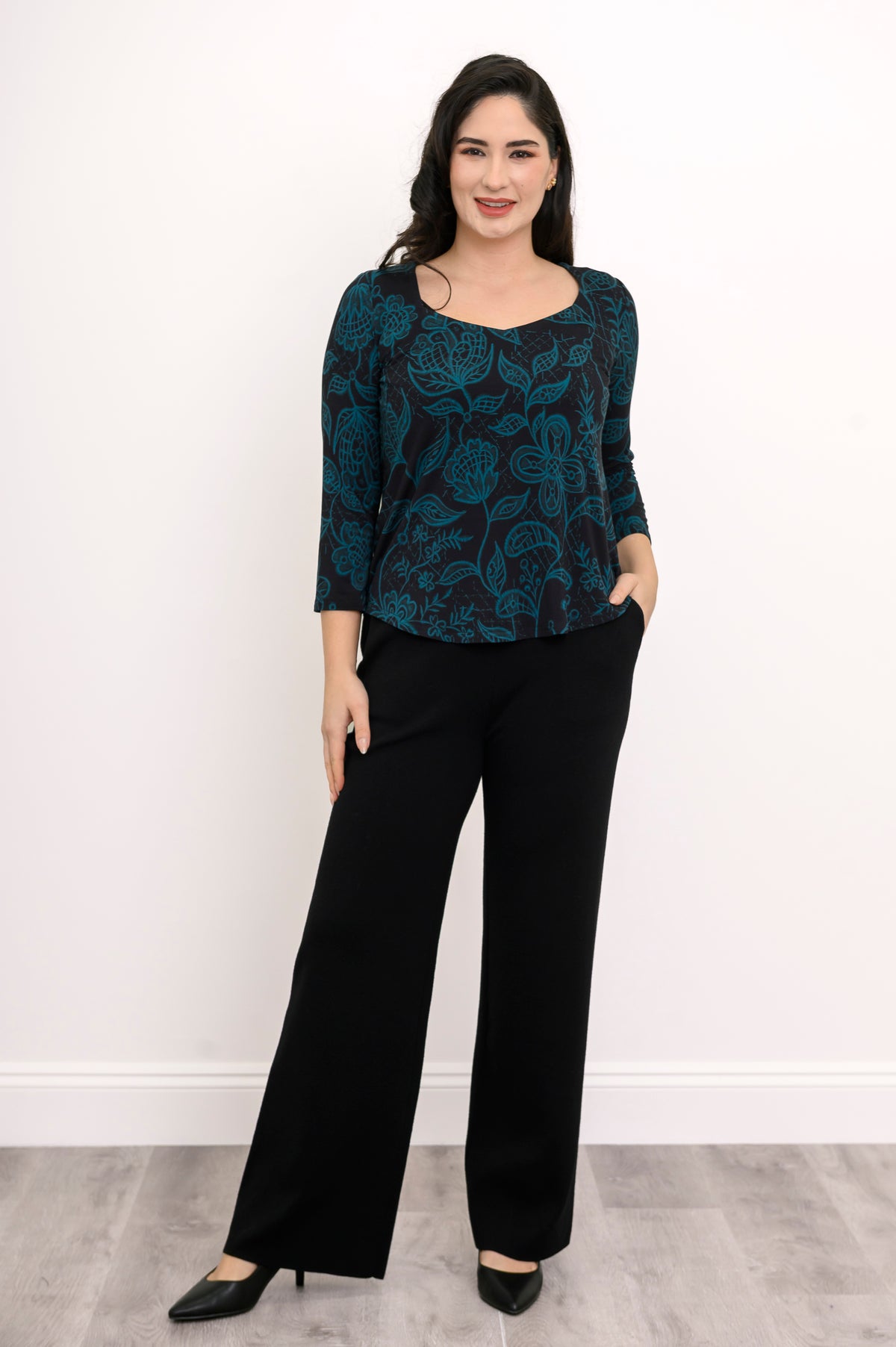 Front view of a dark teal patterned A-line top and black pants, showcasing a relaxed and fluid silhouette.