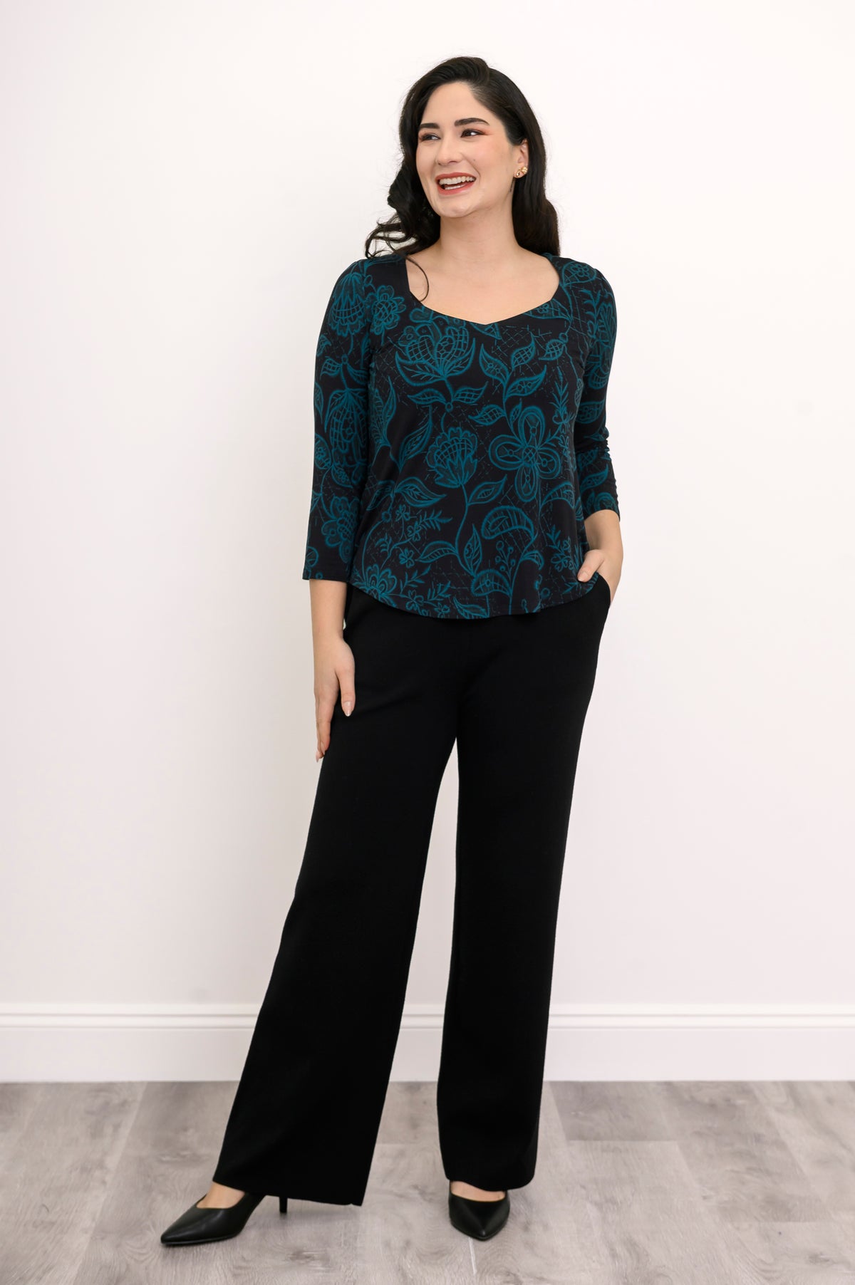 Draped teal leaf pattern pullover shirt with 3/4 sleeves, styled against a simple white background.