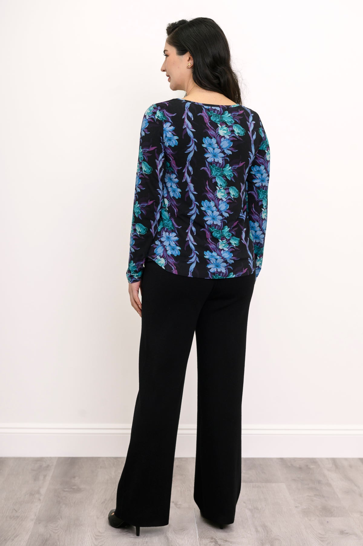 Back view of a teal and black floral print bamboo tunic, showcasing a relaxed-fit drape and curved hemline.