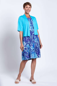Woman wearing blue Roam dress with turquoise short-sleeve open cardigan