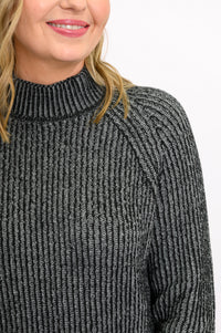 Close-up of a charcoal gray cotton sweater, highlighting the textured two-tone stitch and low mock neck collar.
