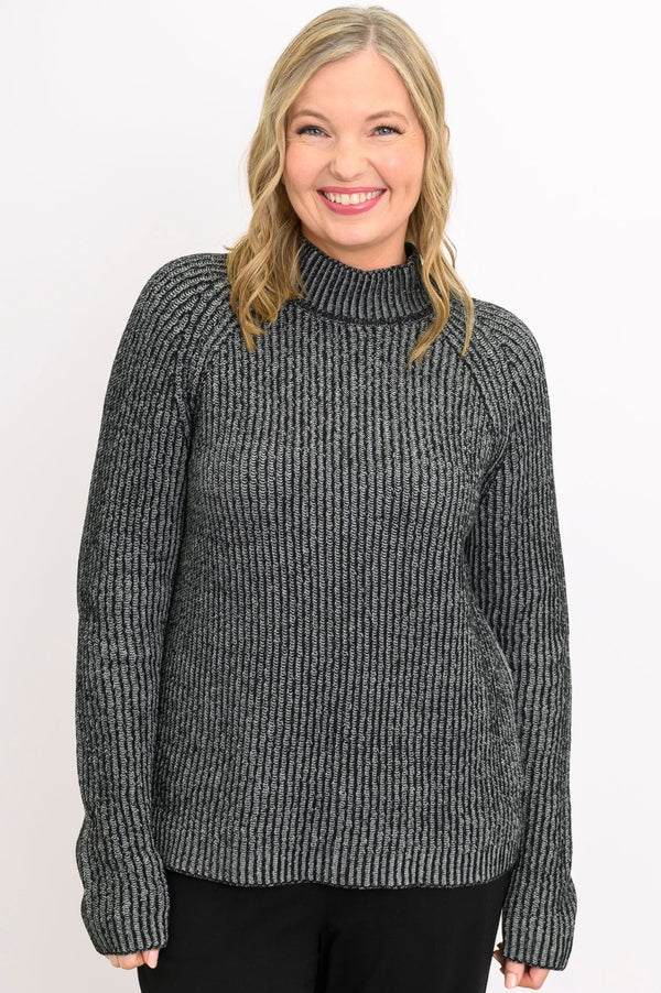 Smiling woman wearing a chunky charcoal gray knit sweater with a low mock neckline and relaxed raglan sleeves.