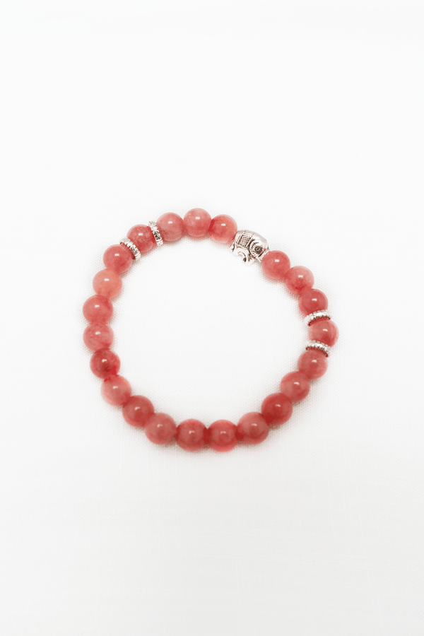 Rose quartz rhodochrosite beaded bracelet with silver fish charm and spacers on a white background