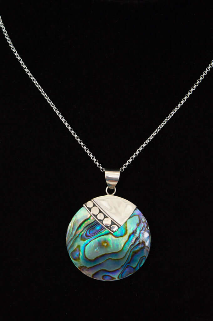 Close-up of a round abalone shell pendant with a silver accent on a sterling silver chain