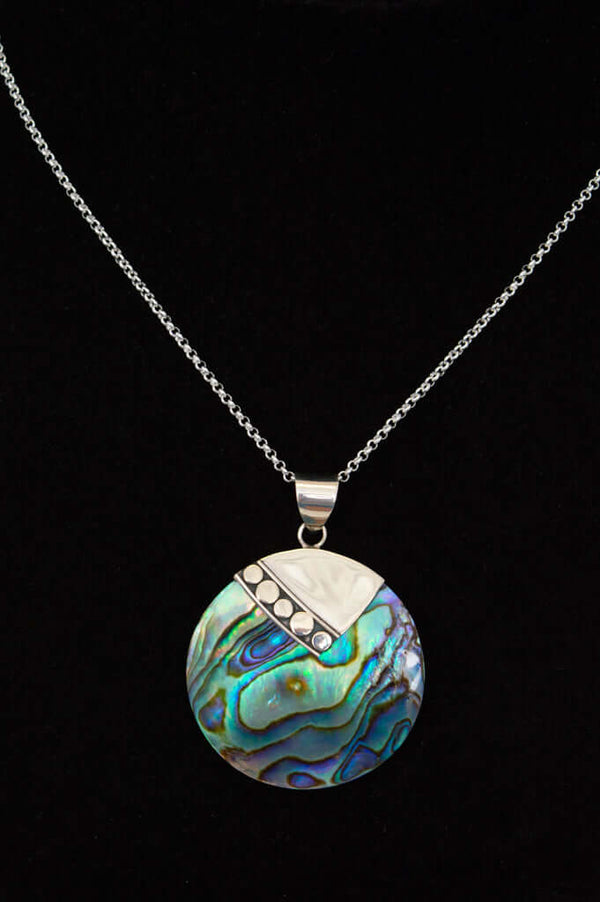 Close-up of a round abalone shell pendant with a silver accent on a sterling silver chain