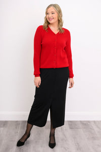 front view of a model in a vibrant red ribbed hem v-neck cardigan sweater and black skirt.
