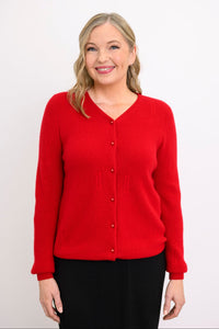 Studio portrait of a smiling woman modeling a bright red long sleeve button up sweater with a high v-neck.