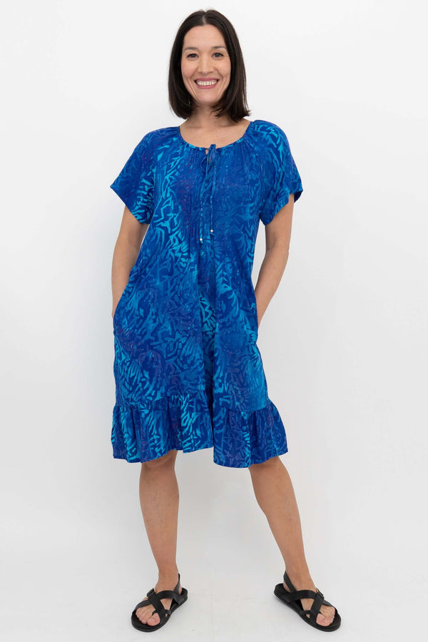 Model showing hands-in-pockets pose in Samoa Dress, vibrant blue pattern