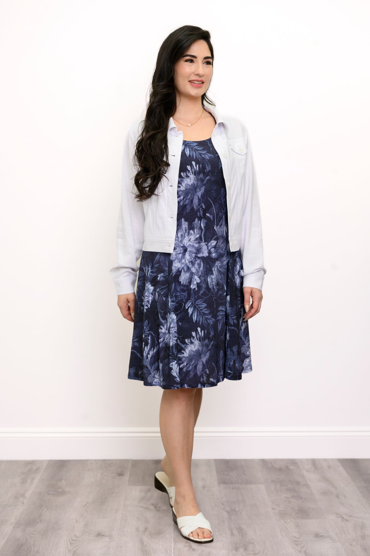 Woman wearing a navy blue floral patterned shirt and white jacket against a white background, front view