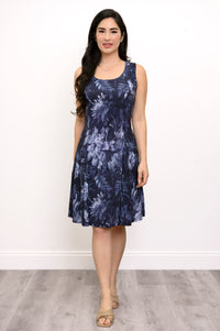 Woman wearing a sleeveless navy floral dress and beige shoes against a white background, front view