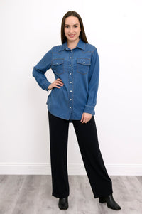 Full body front view of woman wearing denim shirt in western style featuring breast pockets and white buttons