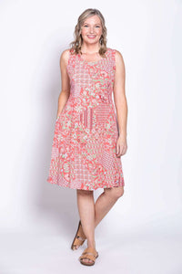 Woman smiling in sleeveless pink patchwork dress with hands in pockets
