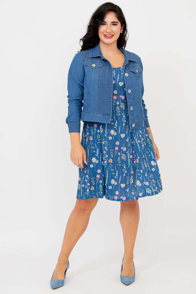 Woman wearing blue floral summer dress styled with a denim jacket and blue heels