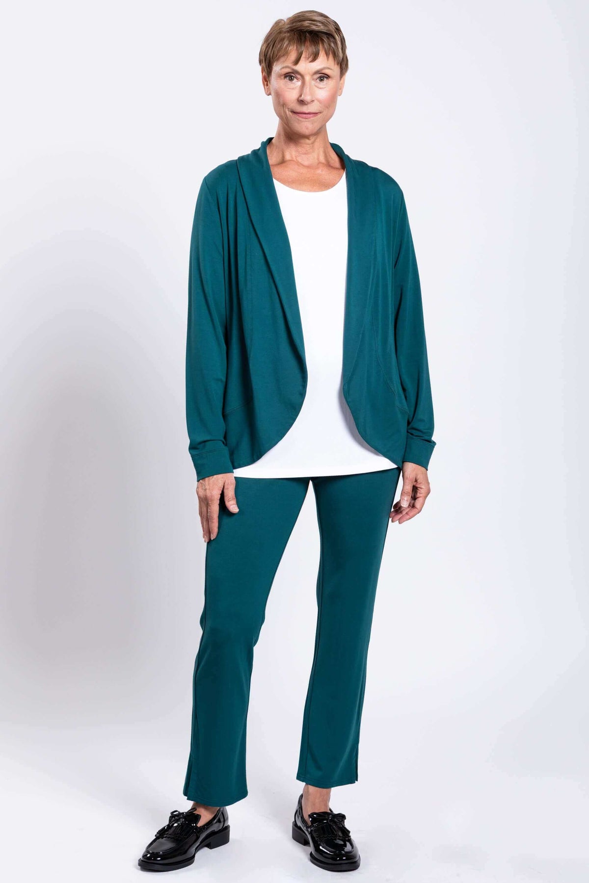 Model wearing a teal Sarina Pant and matching teal jacket with white top