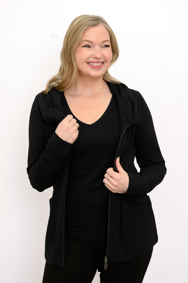 Front view of woman wearing black hooded jacket with pockets, a black top, and black pants on a white background