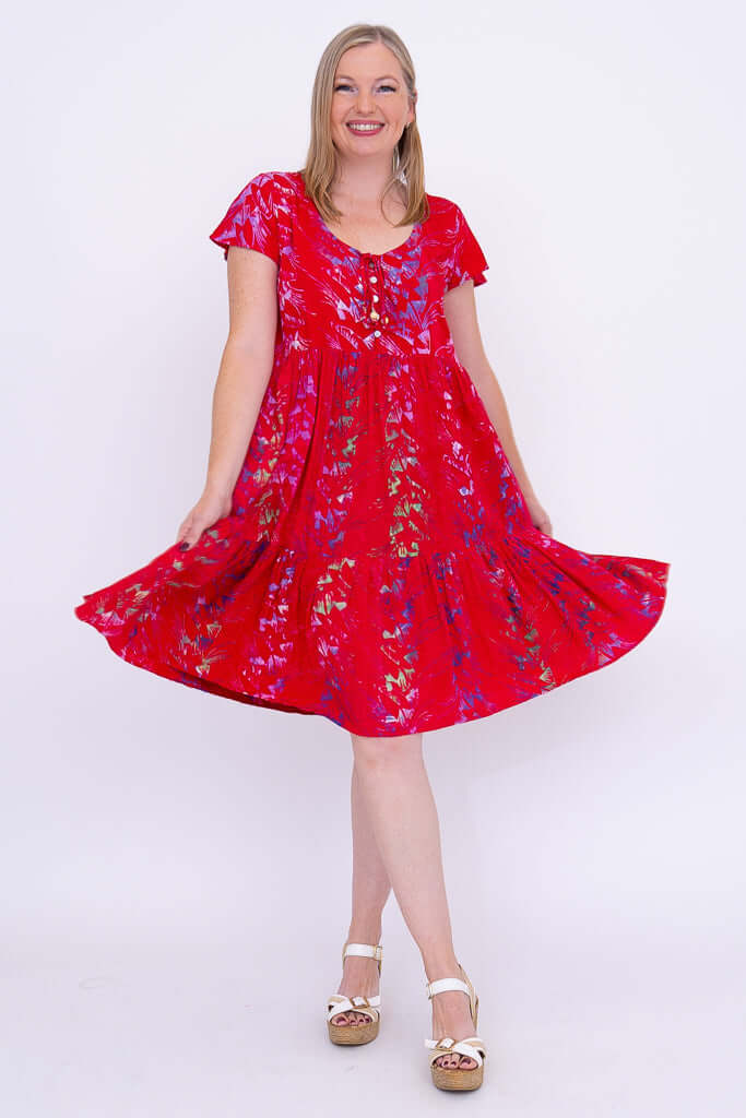 Woman twirling in red flutter sleeve dress with vibrant print