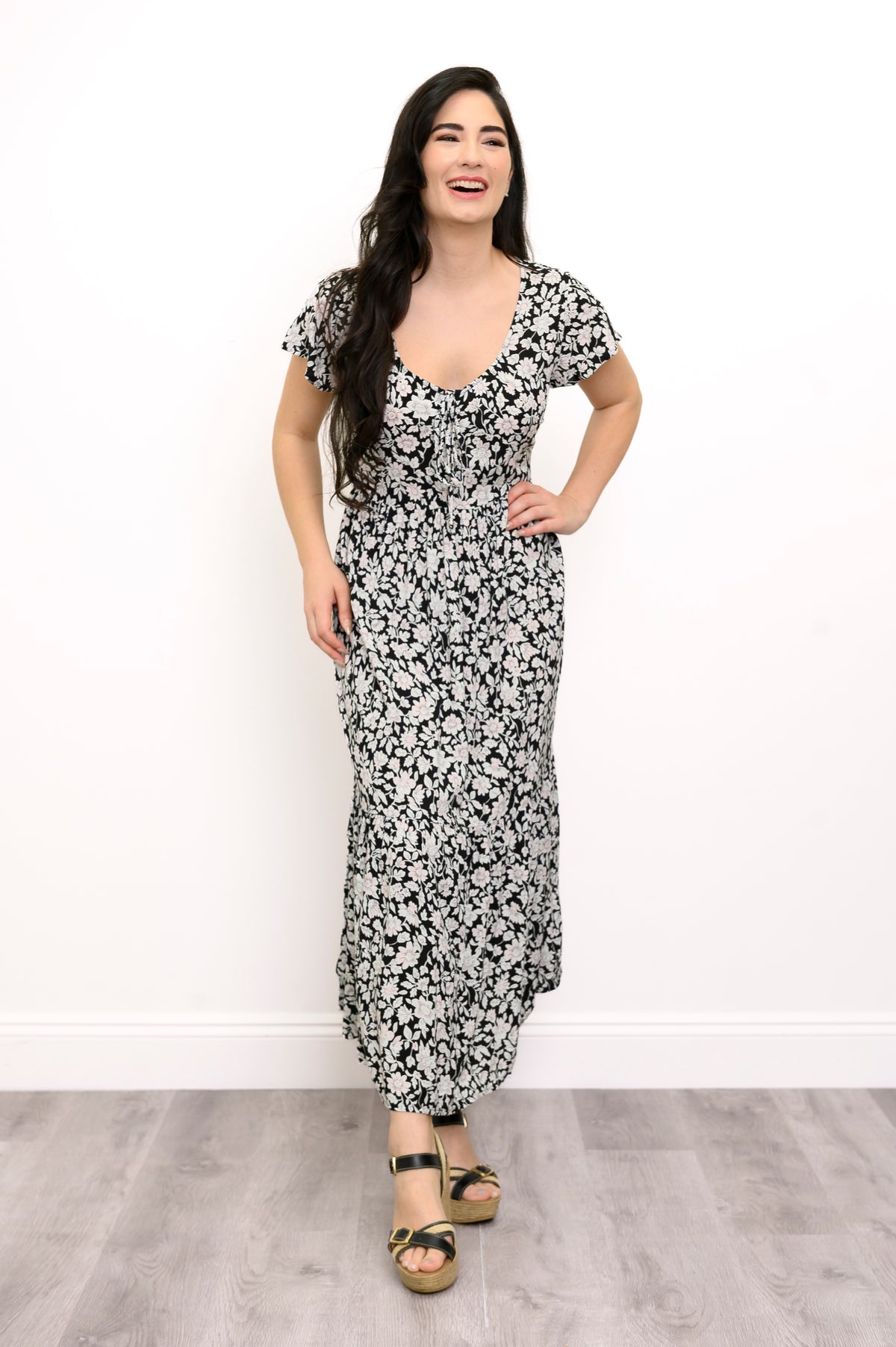 Woman wearing a black and white floral maxi dress and sandals on a white background, front view