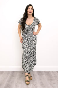 Woman wearing a black and white floral maxi dress and sandals on a white background, front view