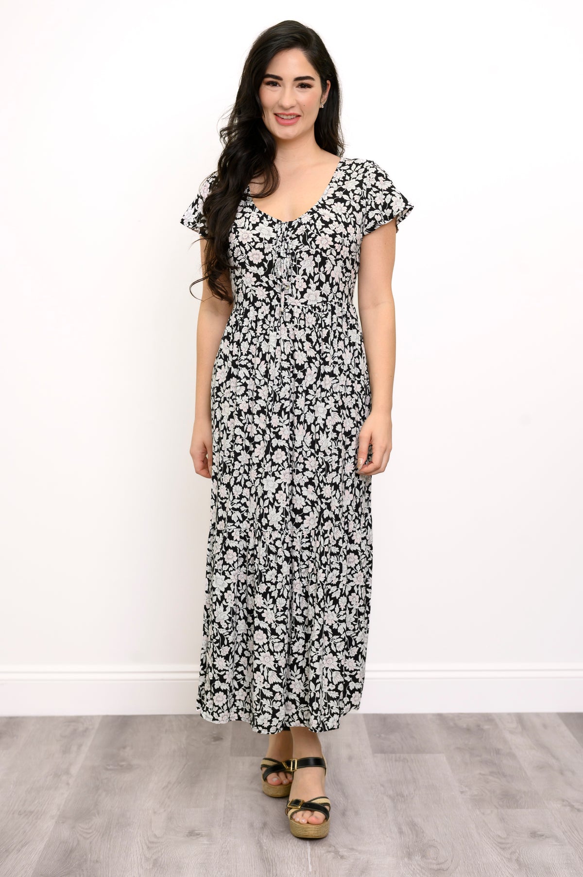 Woman wearing a black and white floral maxi dress and sandals on a white background, front view