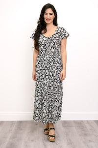 Woman wearing a black and white floral maxi dress and sandals on a white background, front view