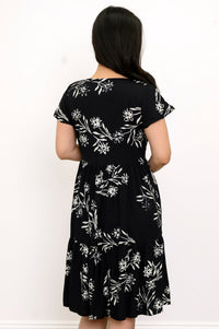 Back view of woman with her hair pushed to the side and wearing a short-sleeve black dress with white flowers on it