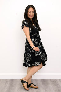 Woman angled slightly to the side and modeling a black short-sleeve floral dress