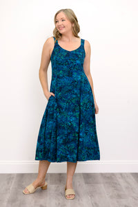 Woman wearing a blue patterned dress and sandals against a white background, front view