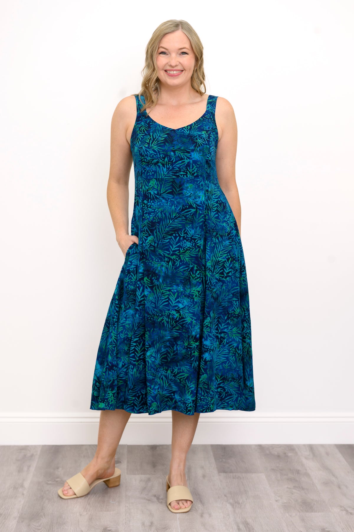 Woman wearing a blue patterned dress and sandals against a white background, front view