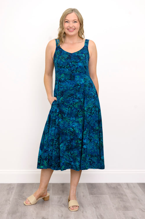 Woman wearing a blue patterned dress and sandals against a white background, front view