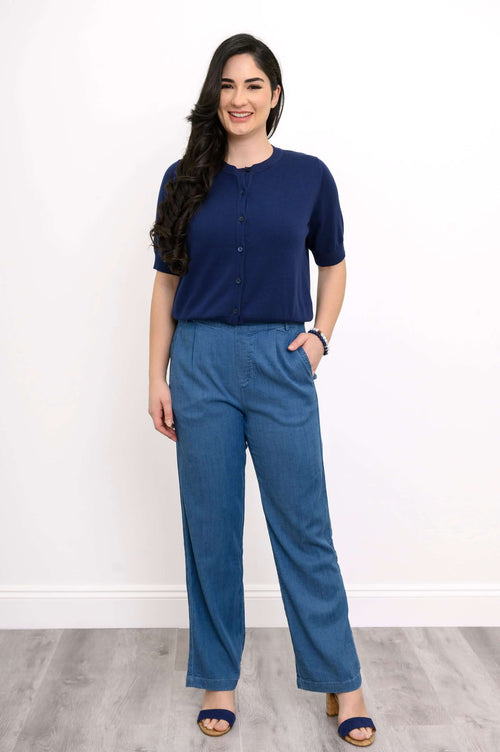 Full body view of woman in Shen indigo cardigan and blue pants, standing on wood floor