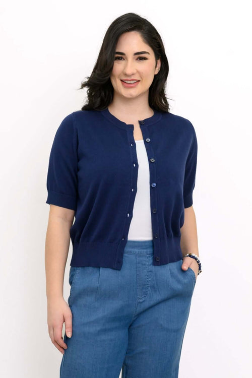Woman wearing Shen short sleeve indigo cardigan with blue pants, front view