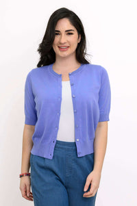 Woman wearing a short sleeve light purple cardigan over a white top and blue pants