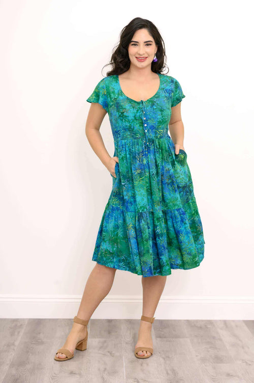 Woman showing pockets in green and blue flutter sleeve midi dress