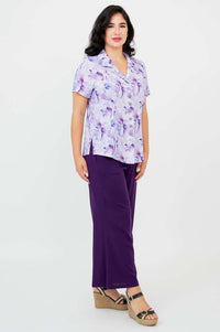 Angled side view of woman in purple watercolor button-up shirt and pants