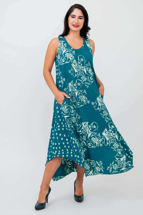 Woman showing side pockets on teal tank dress with white floral print and flowing hem