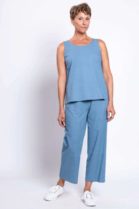 Woman posing in blue sleeveless top and cropped blue pants, turned slightly sideways