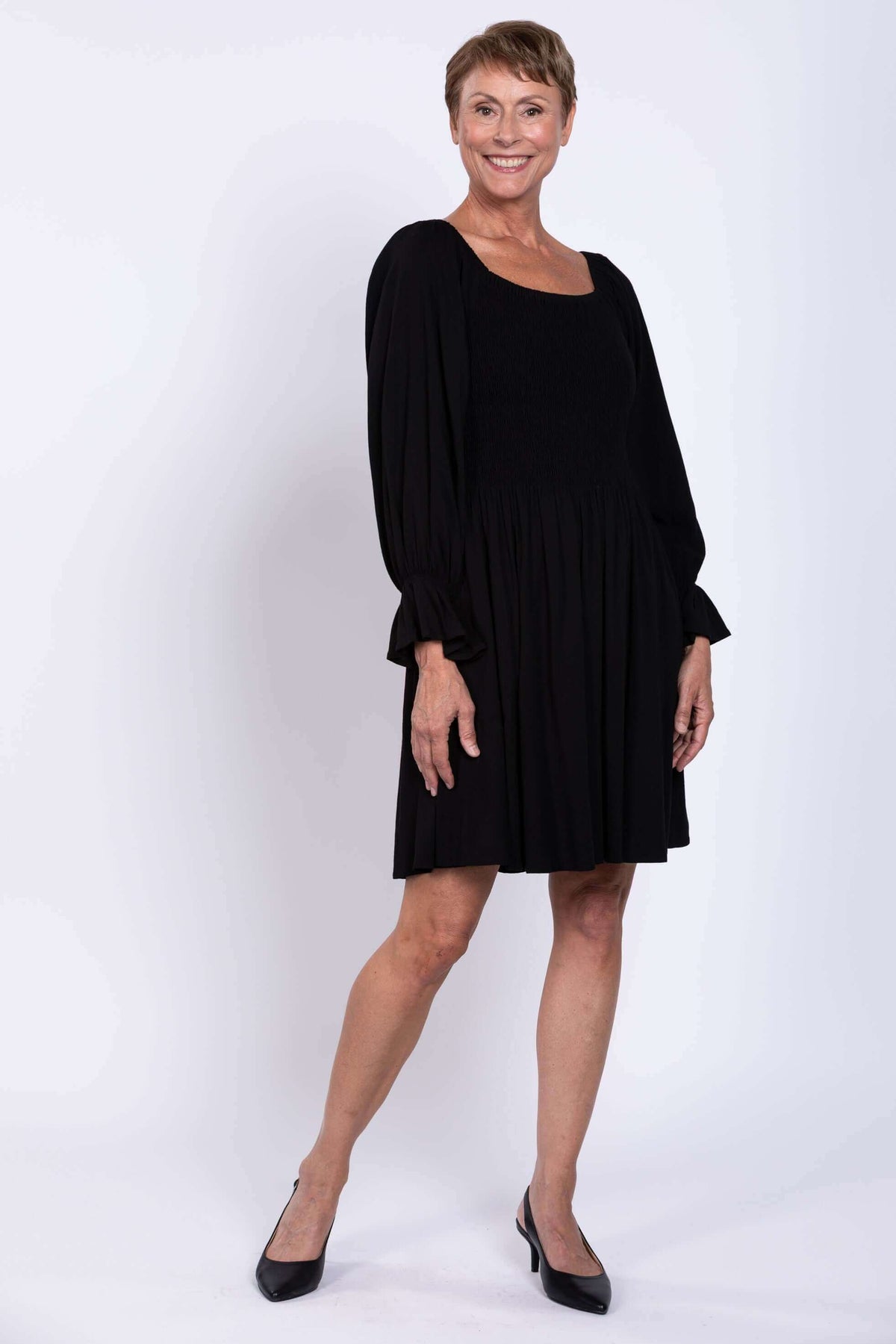 Side view of woman in a black dress with full skirt and long sleeves