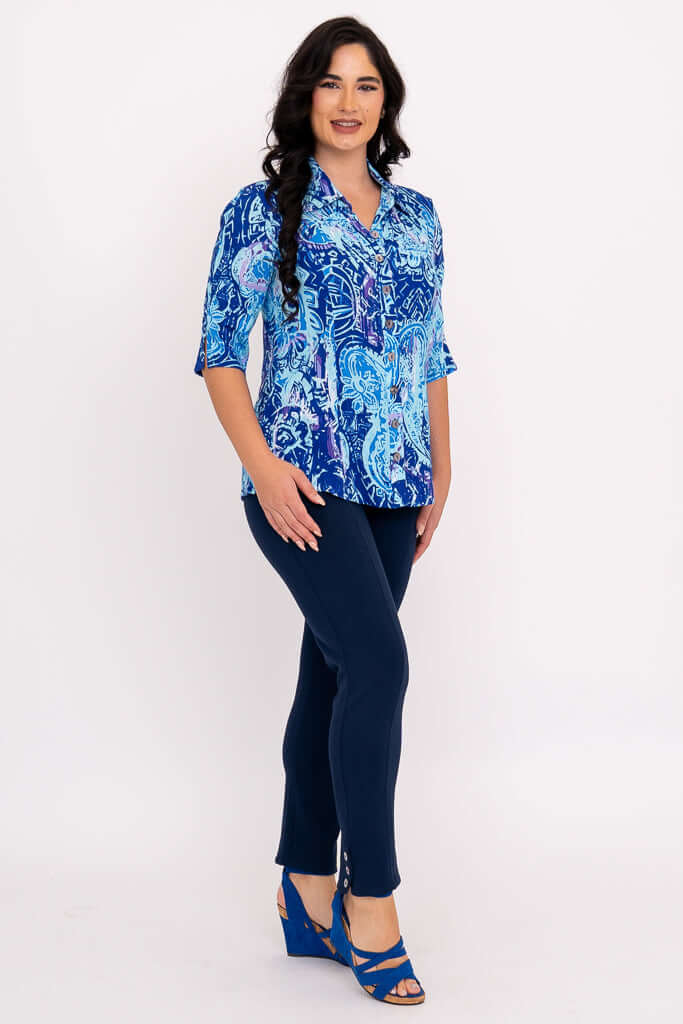 Side angled view of a woman in a blue patterned blouse and navy pants