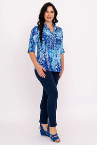 Side angled view of a woman in a blue patterned blouse and navy pants