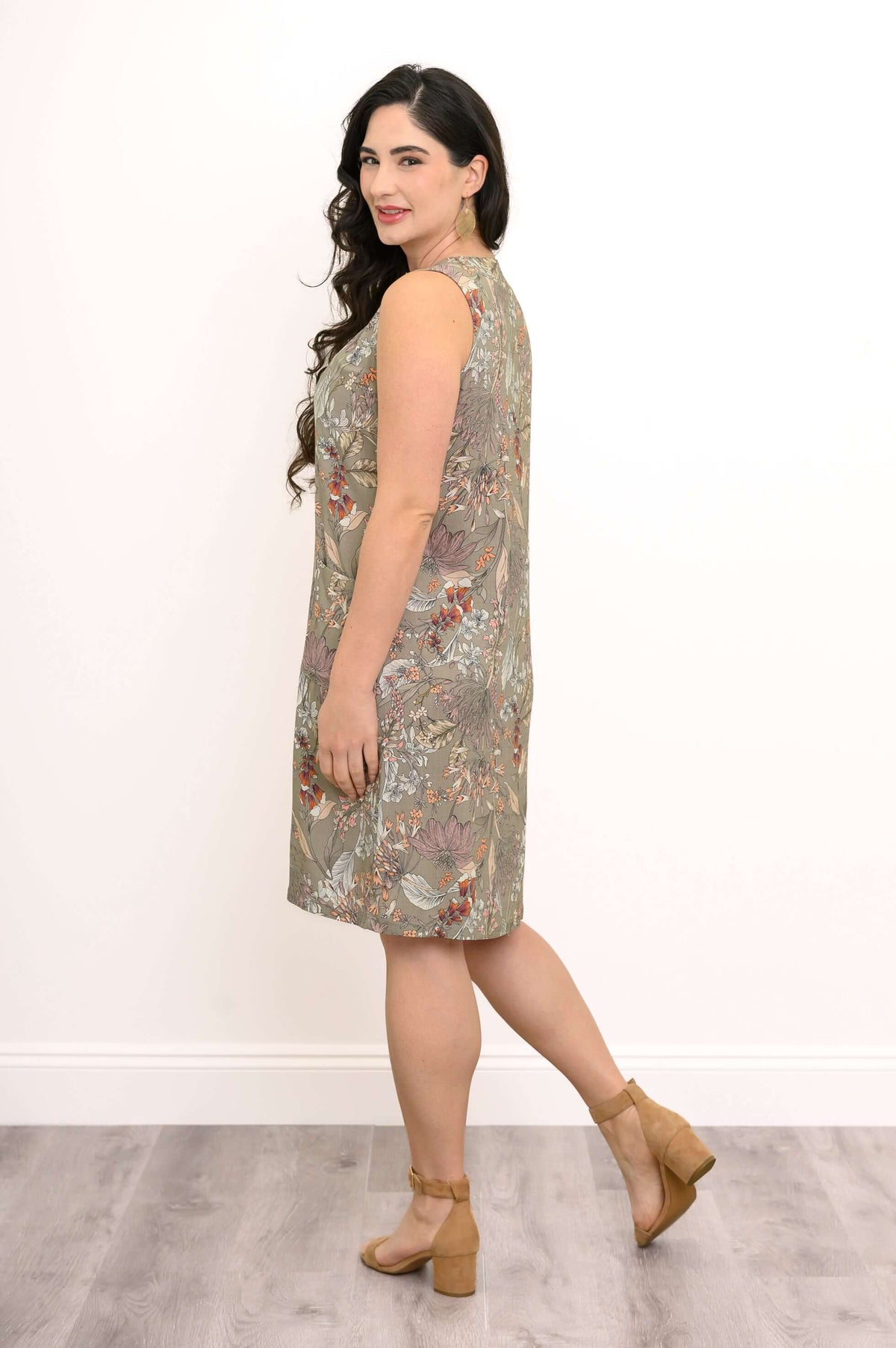Side view of woman in olive floral sleeveless dress, showing split neckline