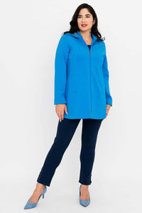 Woman standing in bright blue coat, side view with zipper closed