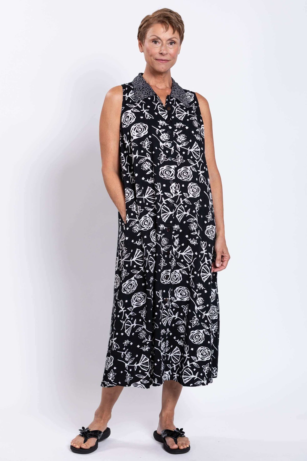 Woman showing side pocket detail on sleeveless black and white floral dress
