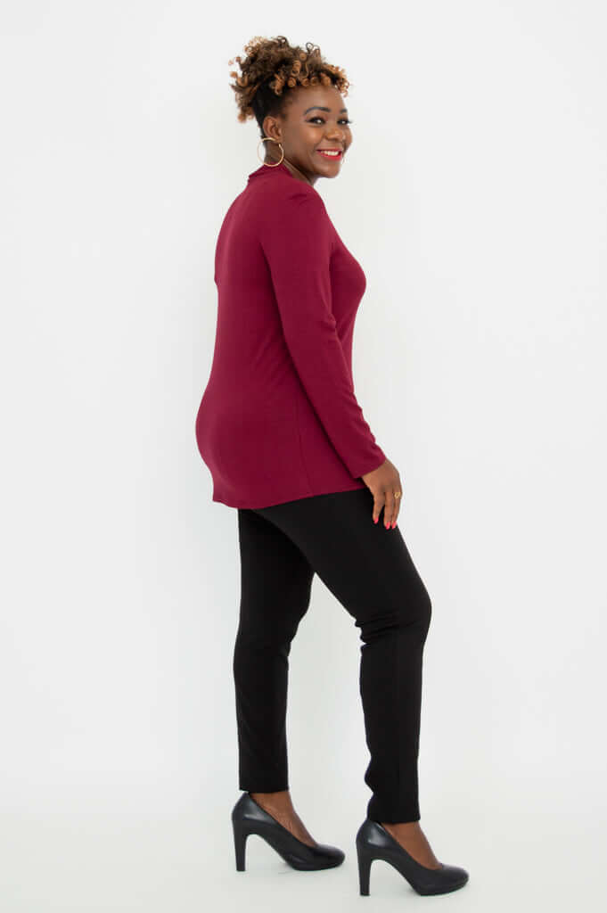 Side profile of woman in burgundy V-neck bamboo top and black pants
