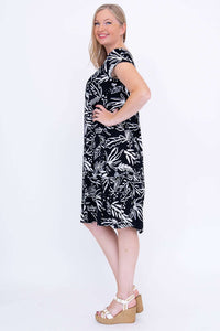 Side view of woman in black and white leafy print dress with hands on hip