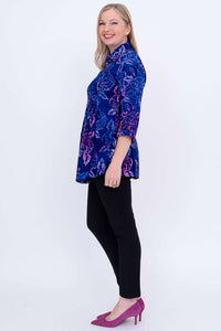 Side view of woman in blue and purple floral tunic and black pants